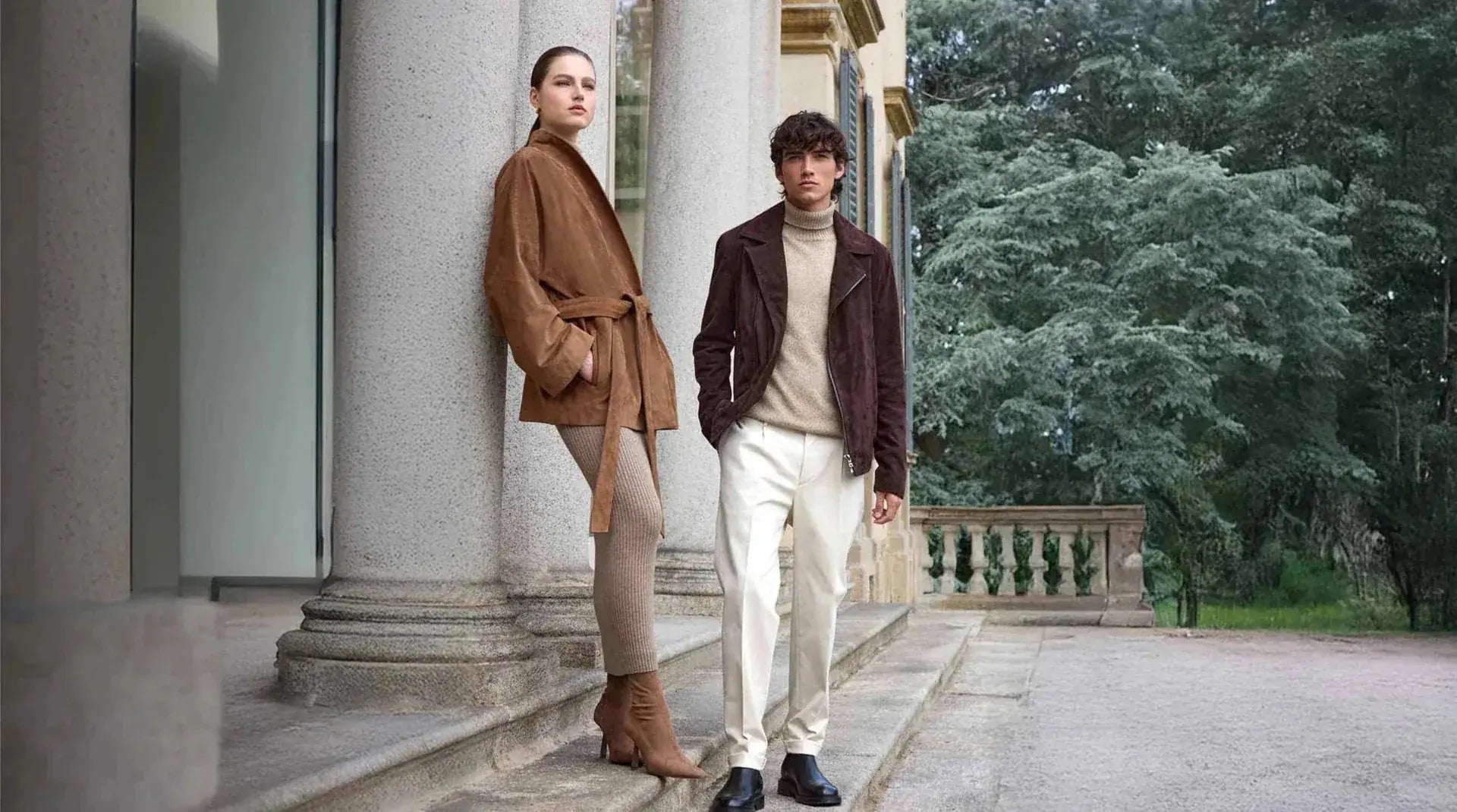 Woman and man wearing brown Orlaven outerwear outside a classical villa